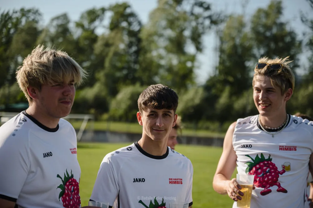 Drei Himbis in weißen Trikots stehen gemeinsam am Spielfeldrand