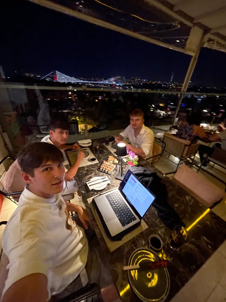 Drei Freunde stehen nachts am DJ-Pult mit Laptop und Mischpult