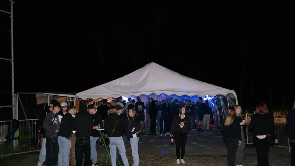 Freunde stehen abends vor dem beleuchteten Festzelt